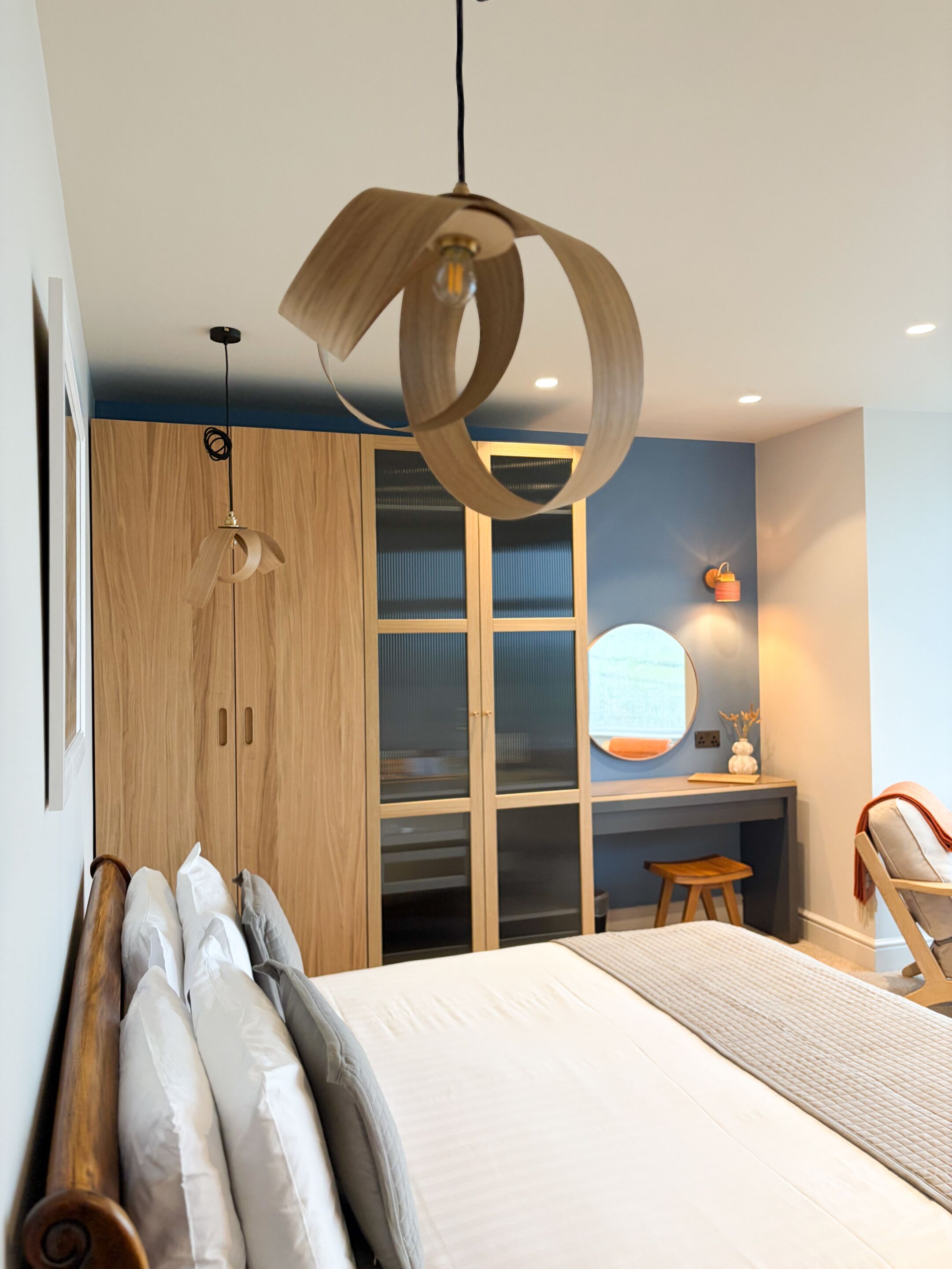 Ein modernes Schlafzimmer mit einem großen Bett, einem Holzschrank und einem Schreibtisch mit Stuhl.