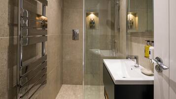 Un baño moderno con cabina de ducha de vidrio, un lavabo blanco y un perchero para toallas.