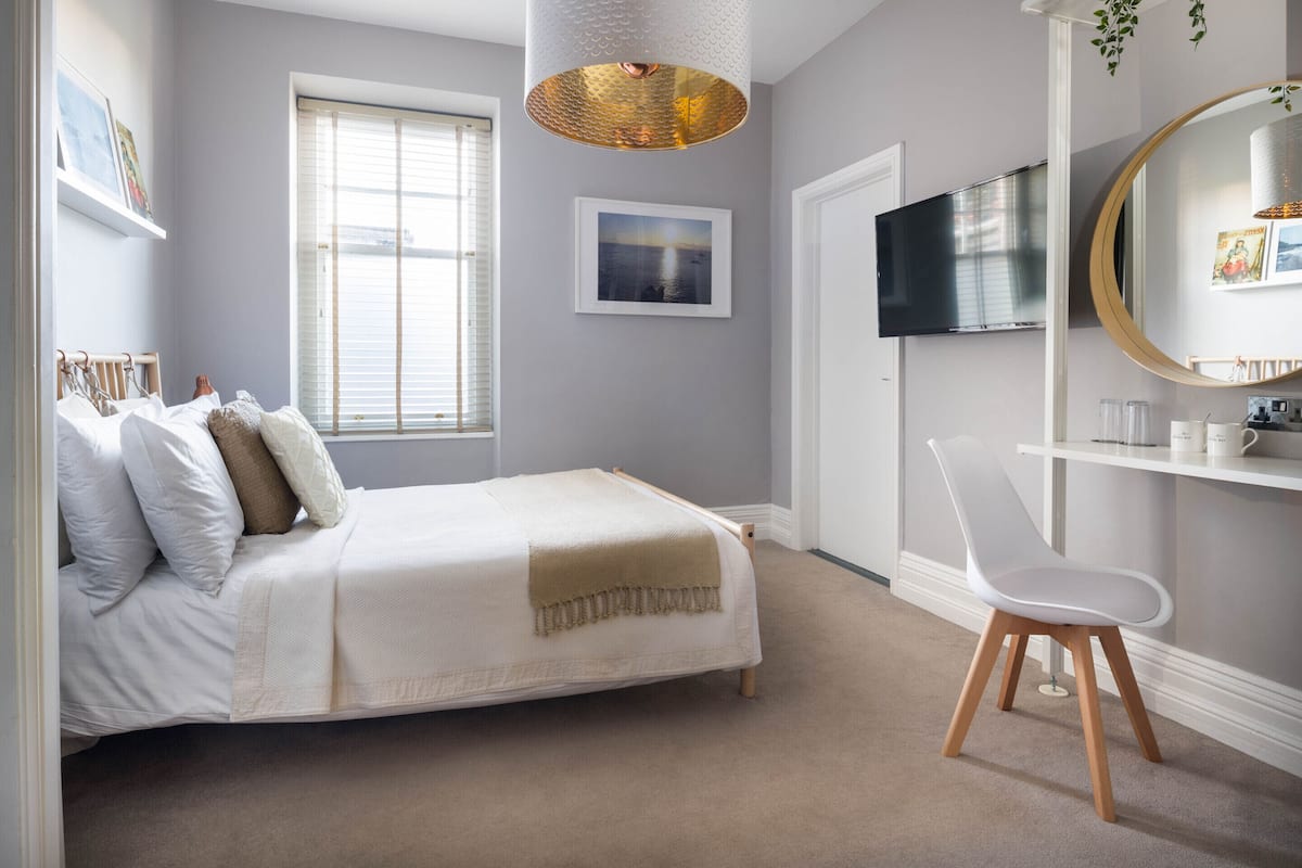 A bedroom with a bed, a chair, a TV, and a shelf with items.