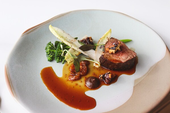 Une assiette de nourriture comprenant un morceau de viande, des légumes et une sauce.