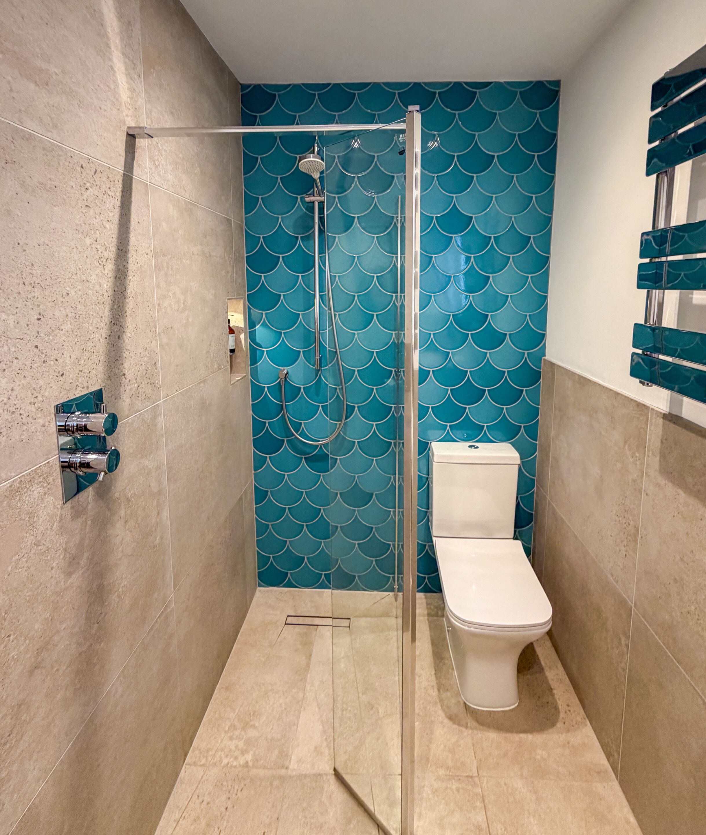 A bathroom with a glass-enclosed shower, a toilet, and a wall with a blue scalloped pattern.