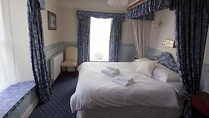 A hotel room with a large bed, a chair, a desk, and a chandelier.