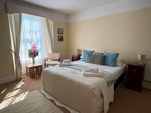 A neatly arranged hotel room with a large bed, a bedside table, a chair, and a window with curtains. - Union Hotel Penzance (Penzance)