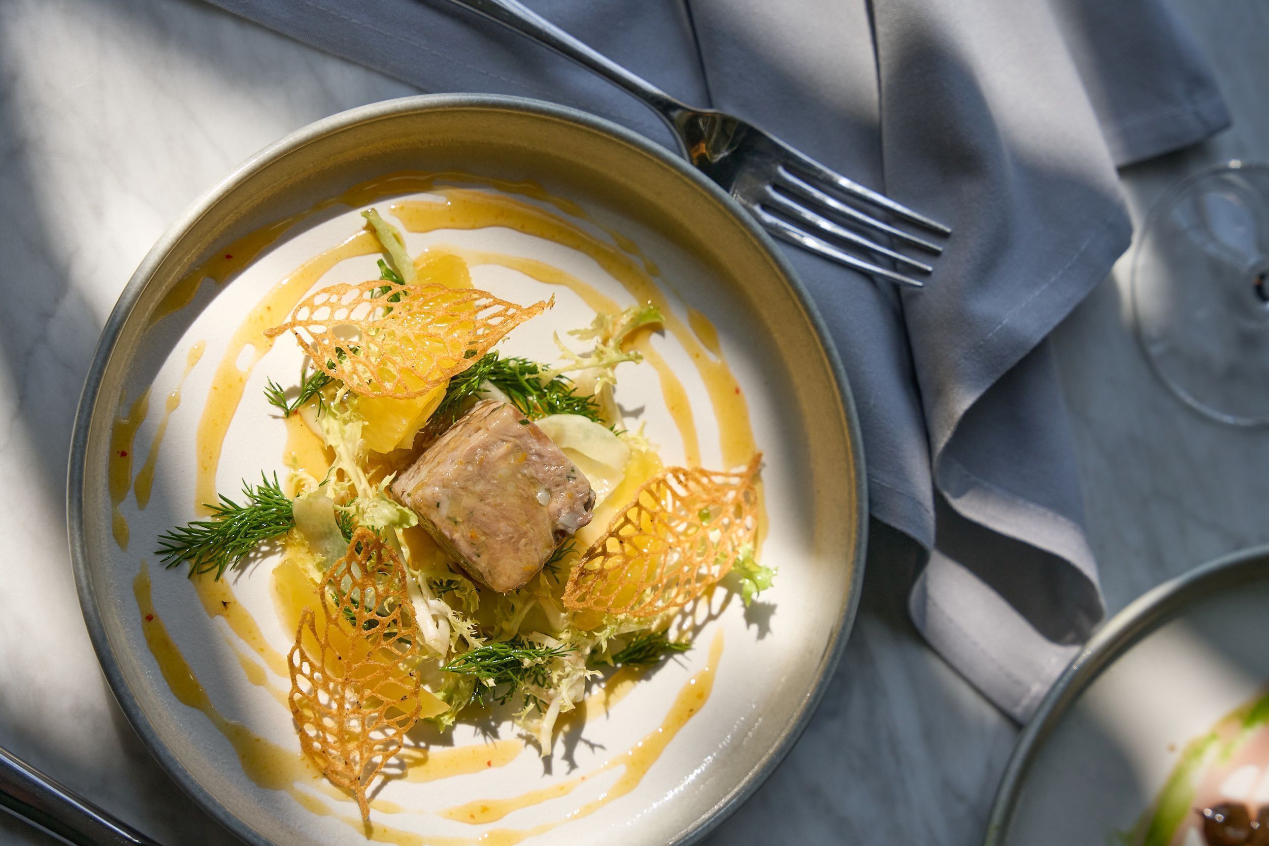 A plate of food with a fork and a glass of water on a table.