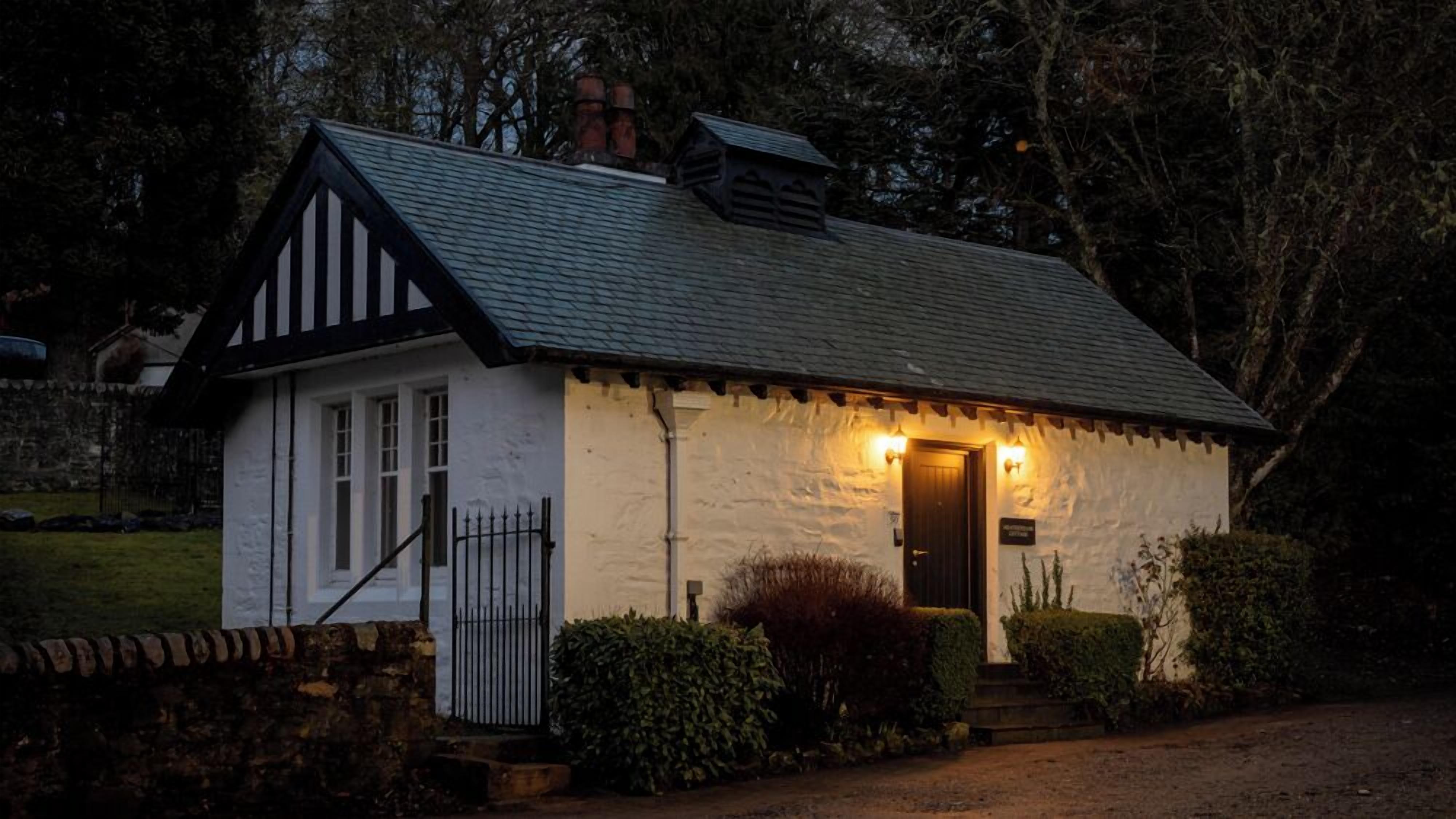 A small, white building with a dark roof, a door, and a small porch area.