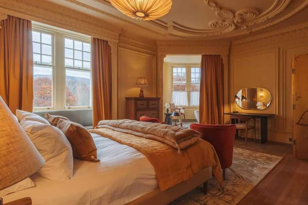A spacious bedroom with a large bed, a desk, and a mirror.