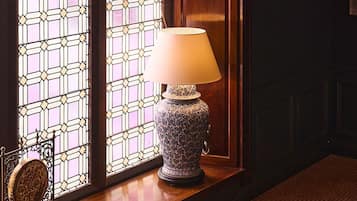 A staircase with a patterned carpet, a lit table lamp, and a stained glass window.