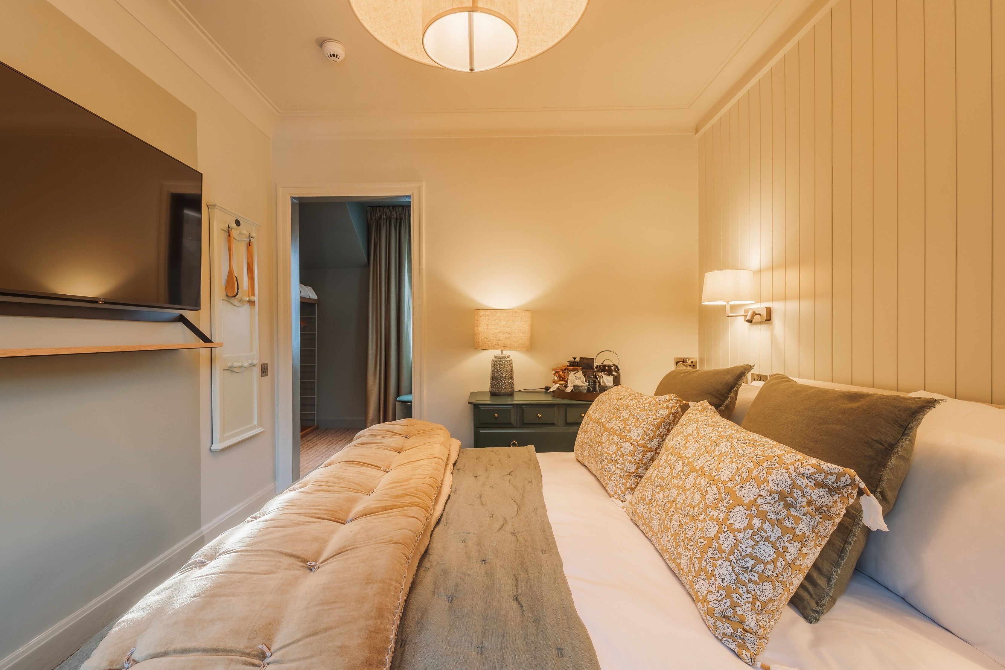 A bedroom with a bed, bedside tables, a lamp, and a television.