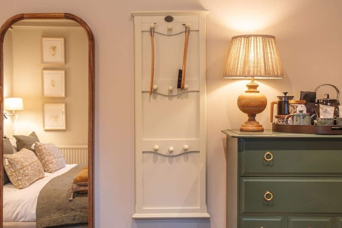 A bedroom with a bed, a dresser, a mirror, and a lamp.