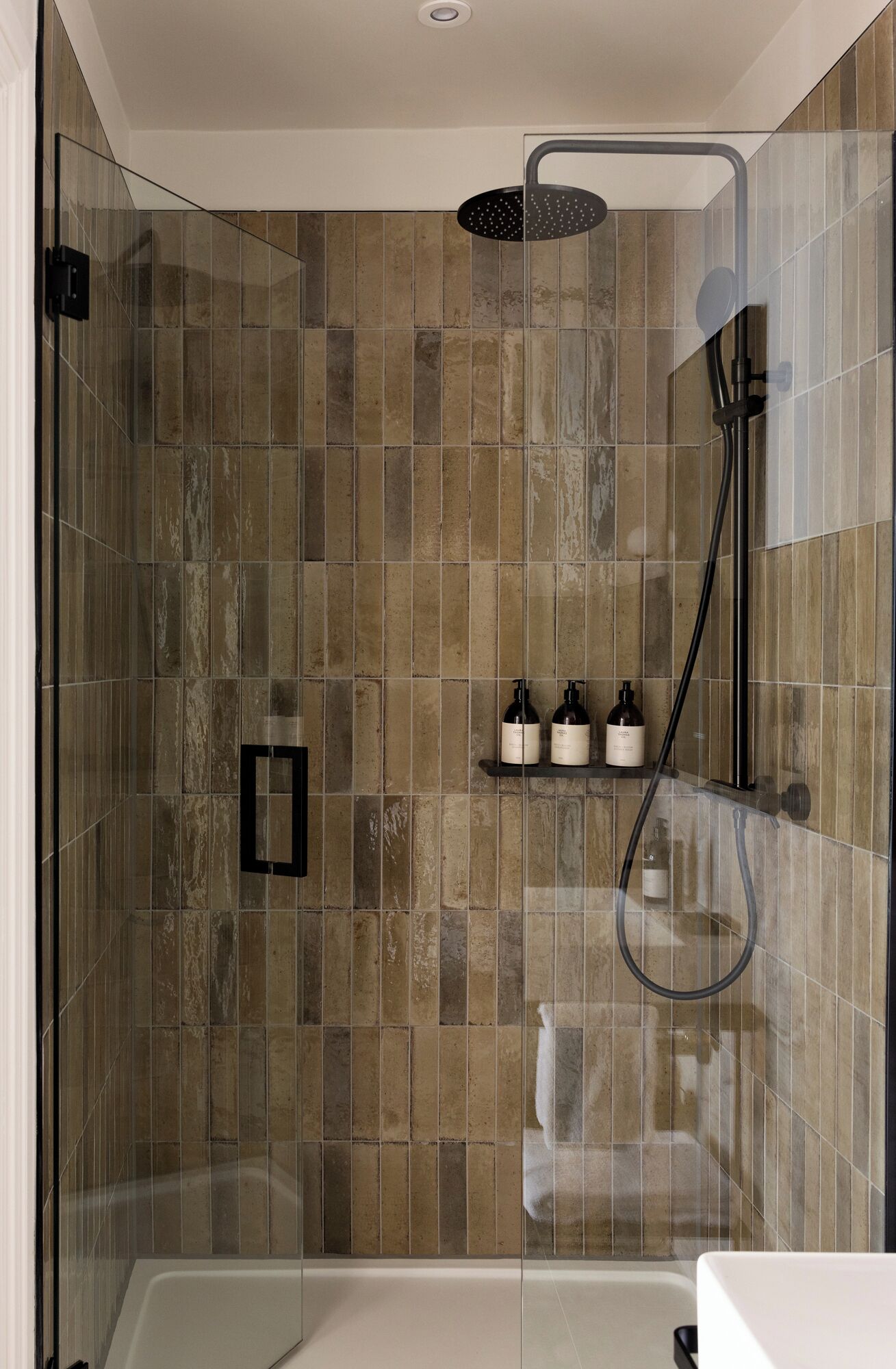 A modern shower with a glass enclosure, a handheld showerhead, and a handheld shower hose.