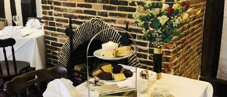 A dining table set for tea with a brick fireplace in the background.