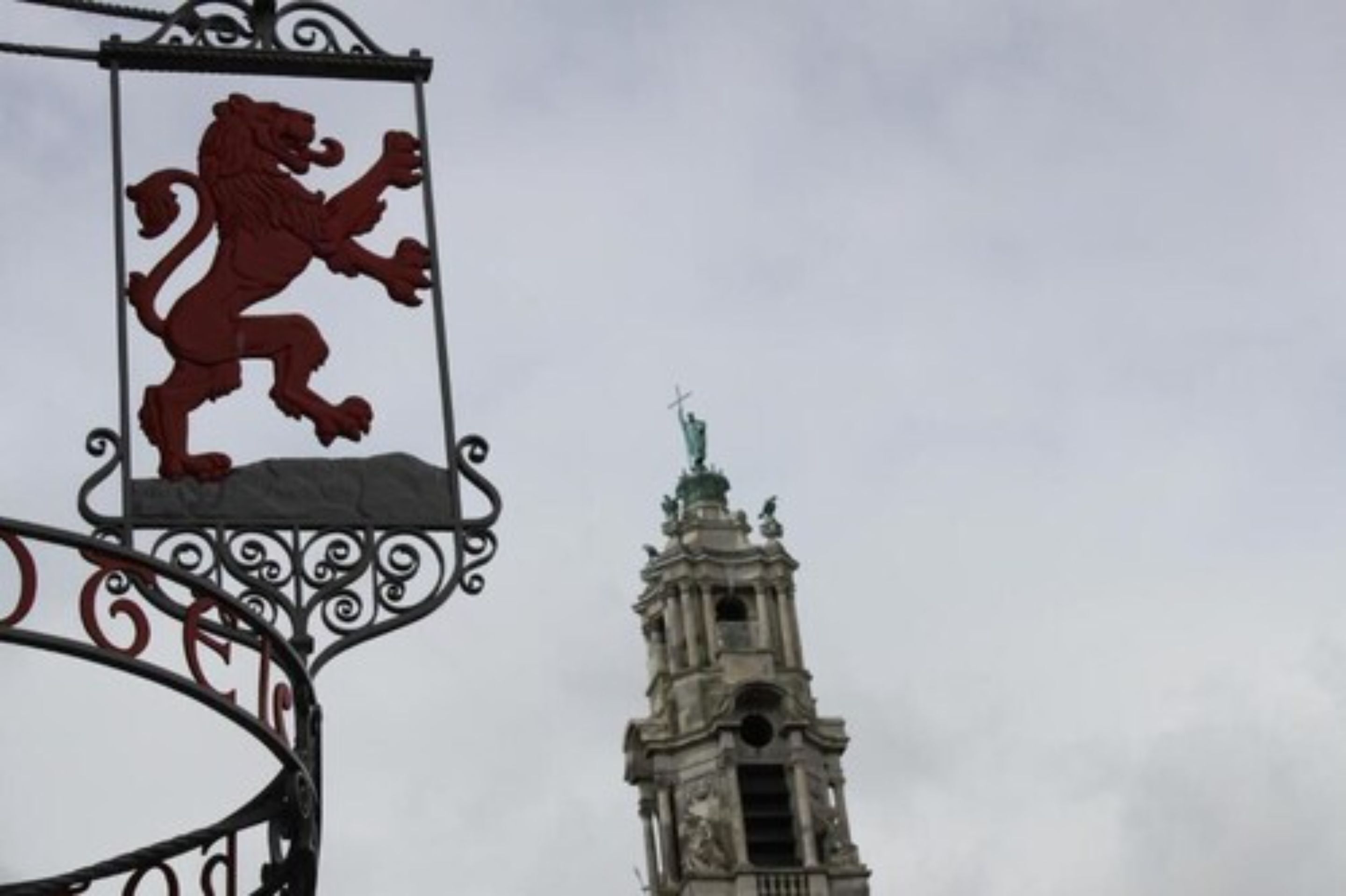 A lion emblem on a metal structure with a historic building in the background.