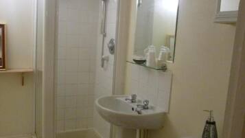 A bathroom with a shower, sink, toilet, and a mirror.
