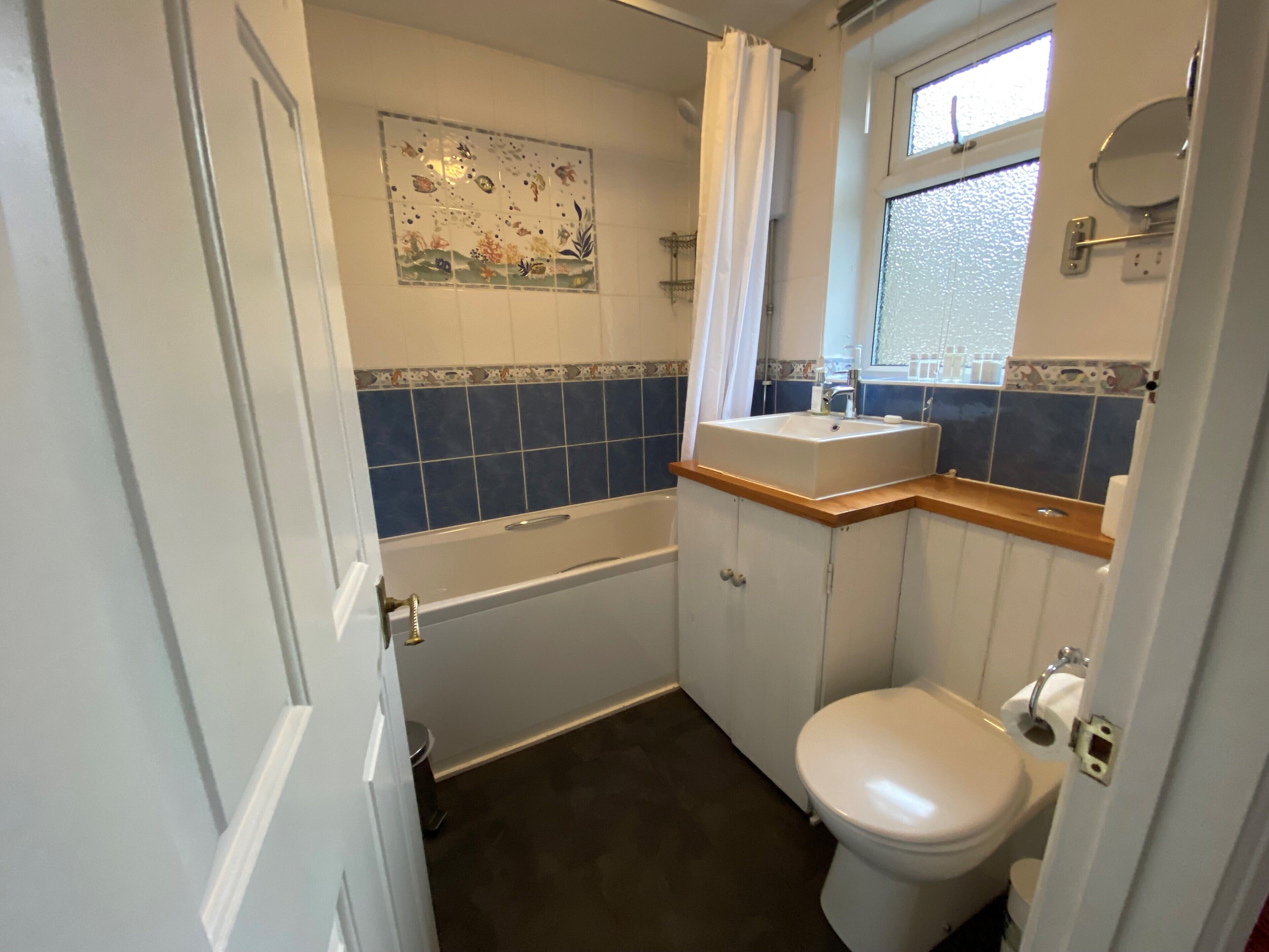A small bathroom with a bathtub, a toilet, a sink, and a window.