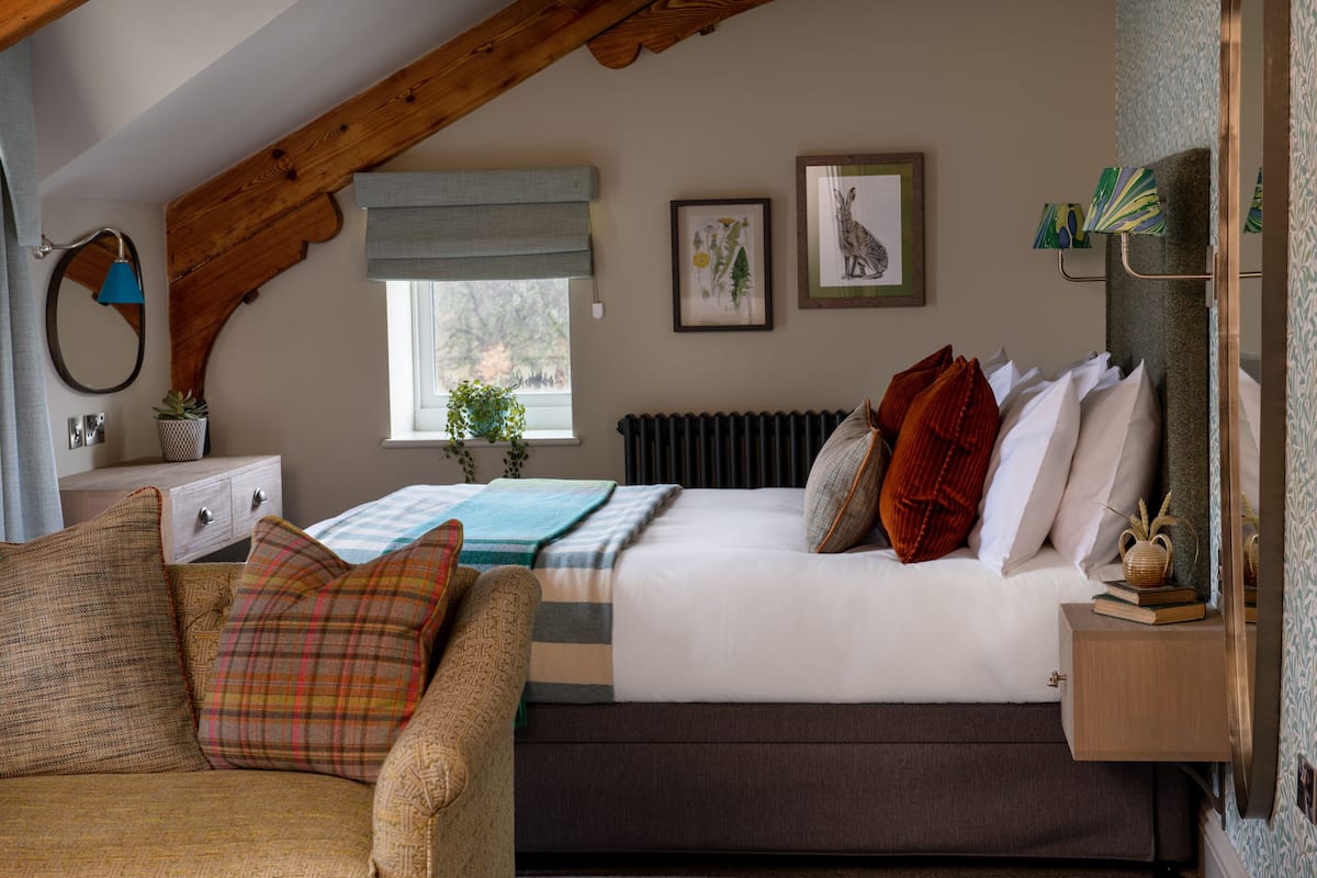 A bedroom with a bed, a nightstand, a chair, a window, and a radiator.