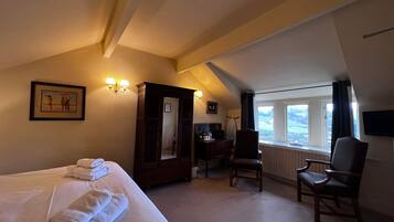A hotel room with a bed, a chair, a desk, a wardrobe, and a window with a view.