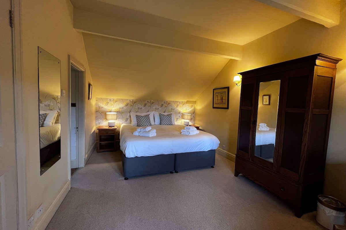 A bedroom with a large bed, bedside tables, a mirror, and a wardrobe.