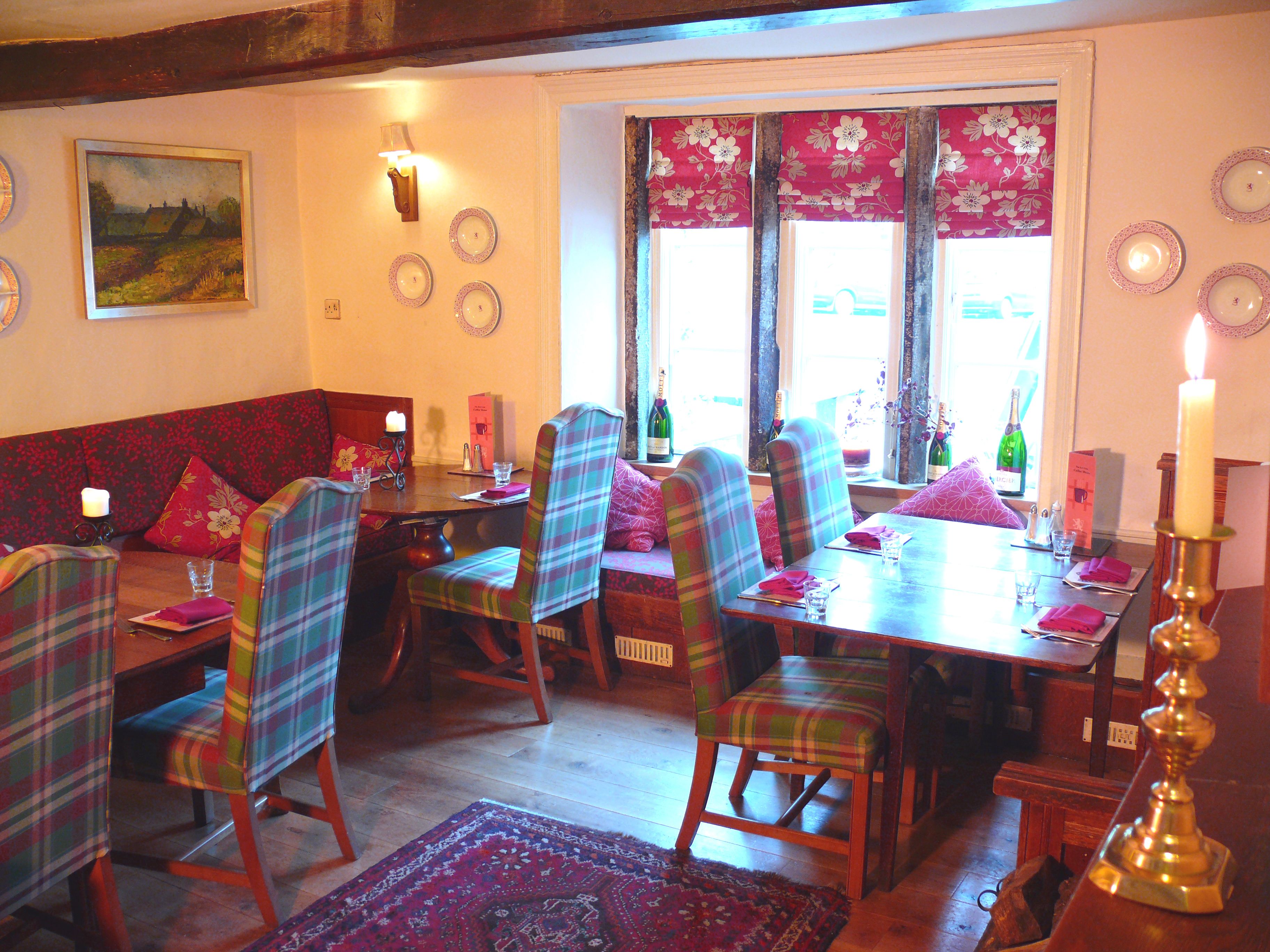 A dining area with plaid chairs, a wooden table, and a red patterned rug.