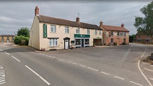 A two-story building with a pub named "The Black Sheep Inn" and a restaurant named "The Green Man." - OYO 4 Sisters Inn (Lincoln)