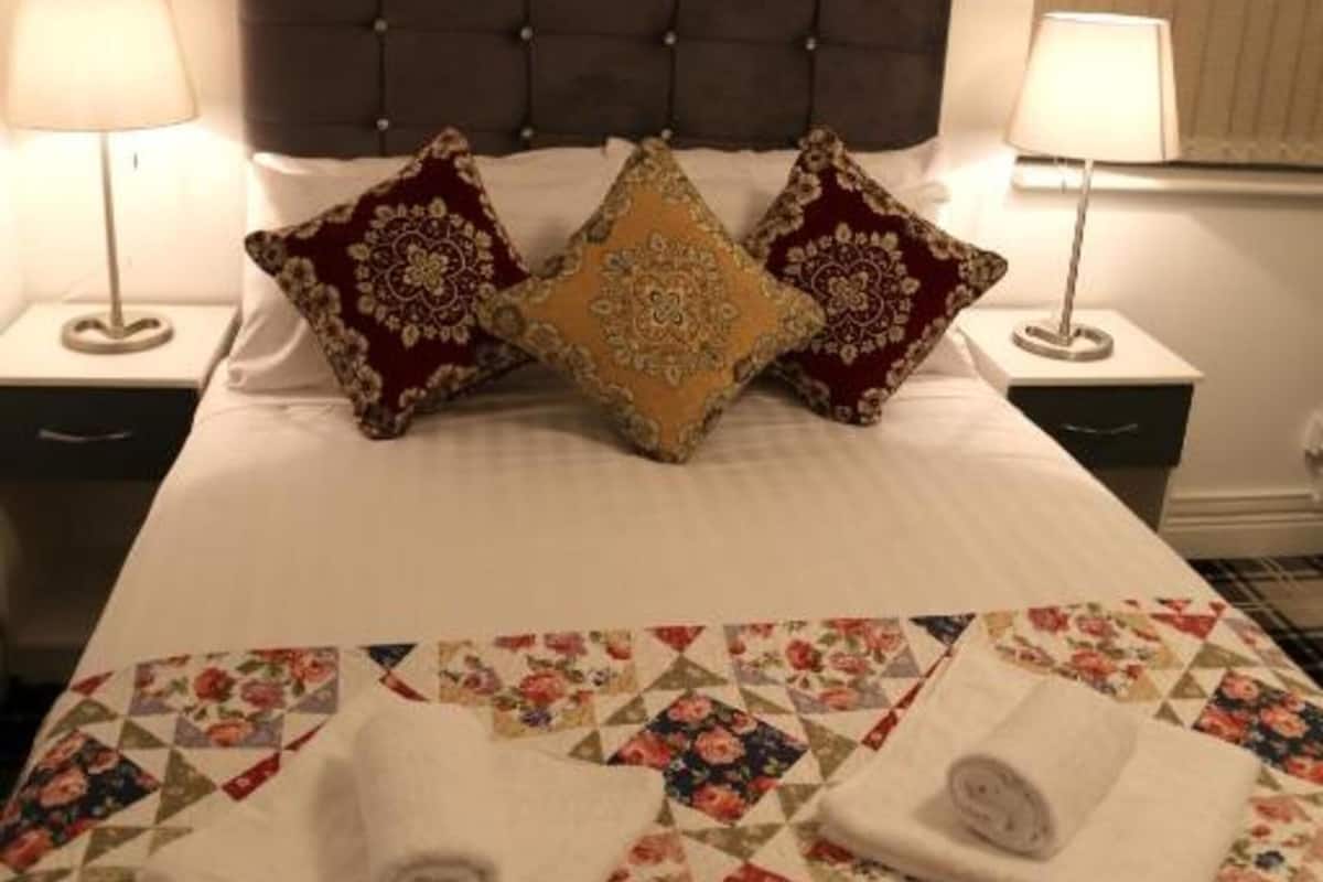 A neatly made bed with a floral quilt, two decorative pillows, and a framed artwork above it.