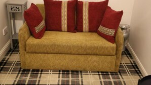 A sofa with red cushions and a plaid floor. - OYO 4 Sisters Inn (Lincoln)