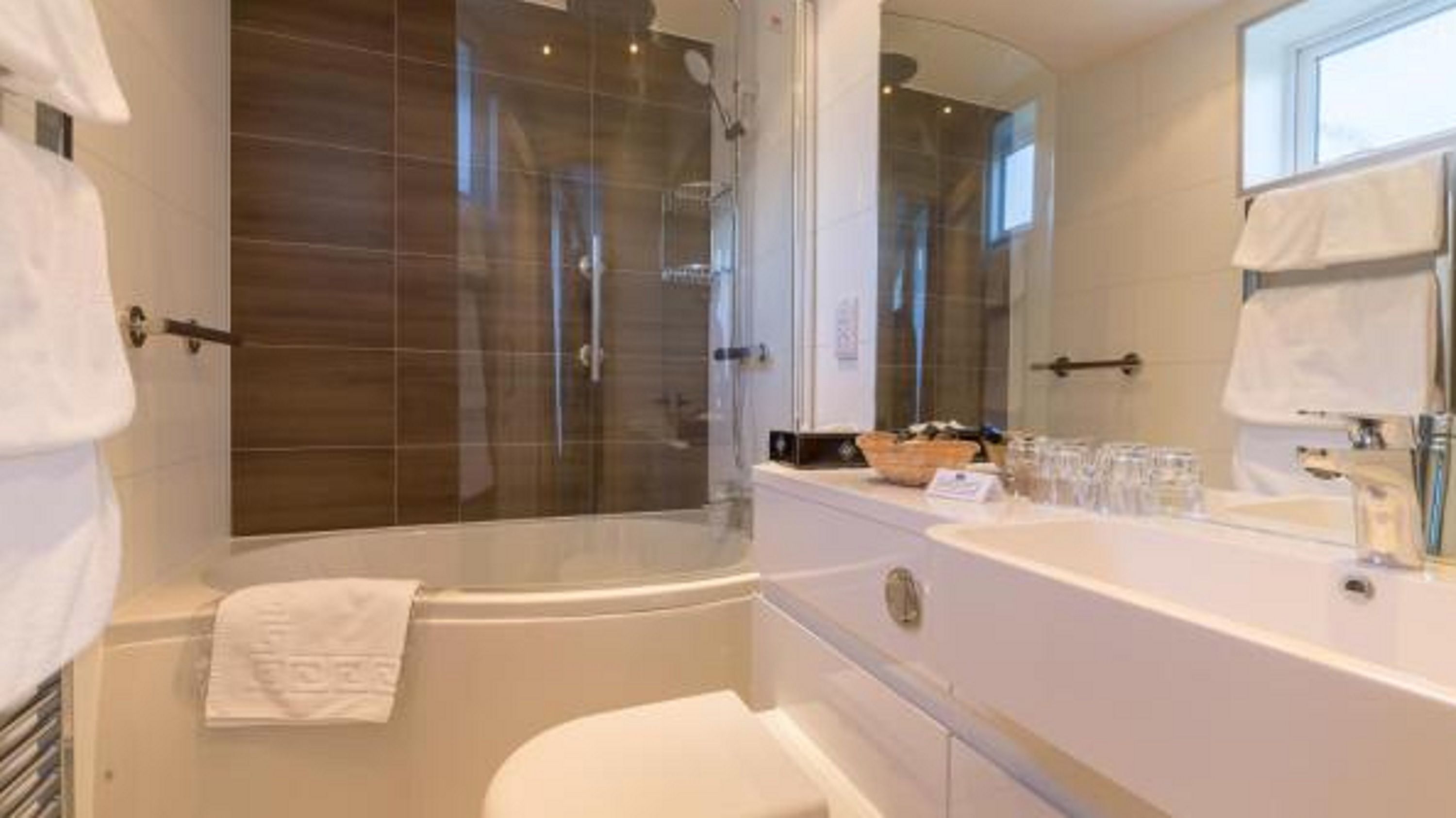 A modern bathroom with a glass-enclosed shower, a bathtub, and a vanity with a large mirror.