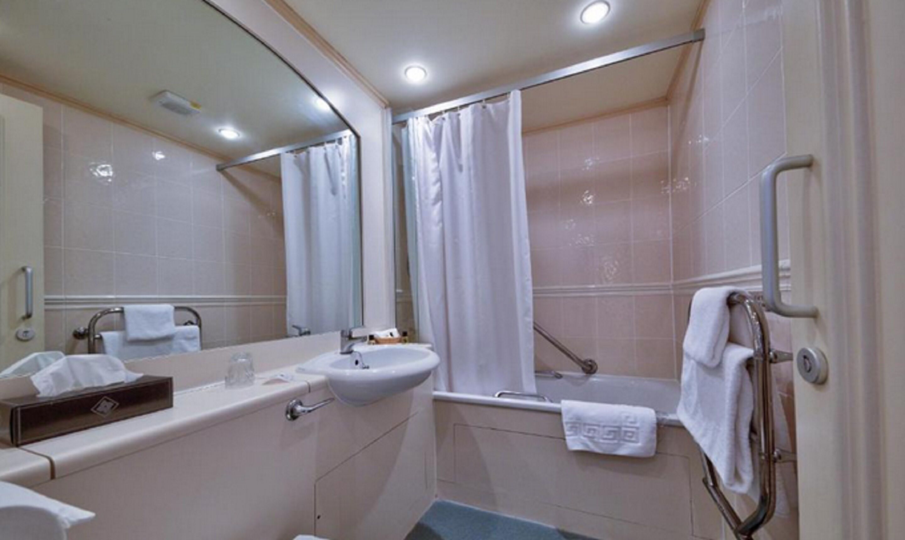 A bathroom with a sink, mirror, and shower.