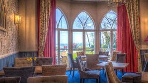 Comedor con vistas al exterior, con ventanas arqueadas y cortinas rojas.