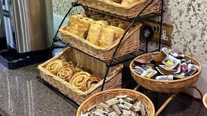 A breakfast buffet with various pastries and packaged goods. - Athena (London)