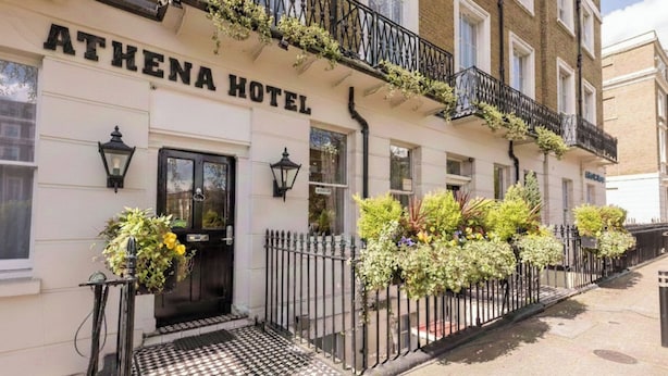 The Athena Hotel facade with a black iron fence, a checkered entrance, and hanging plants. - Athena (London)