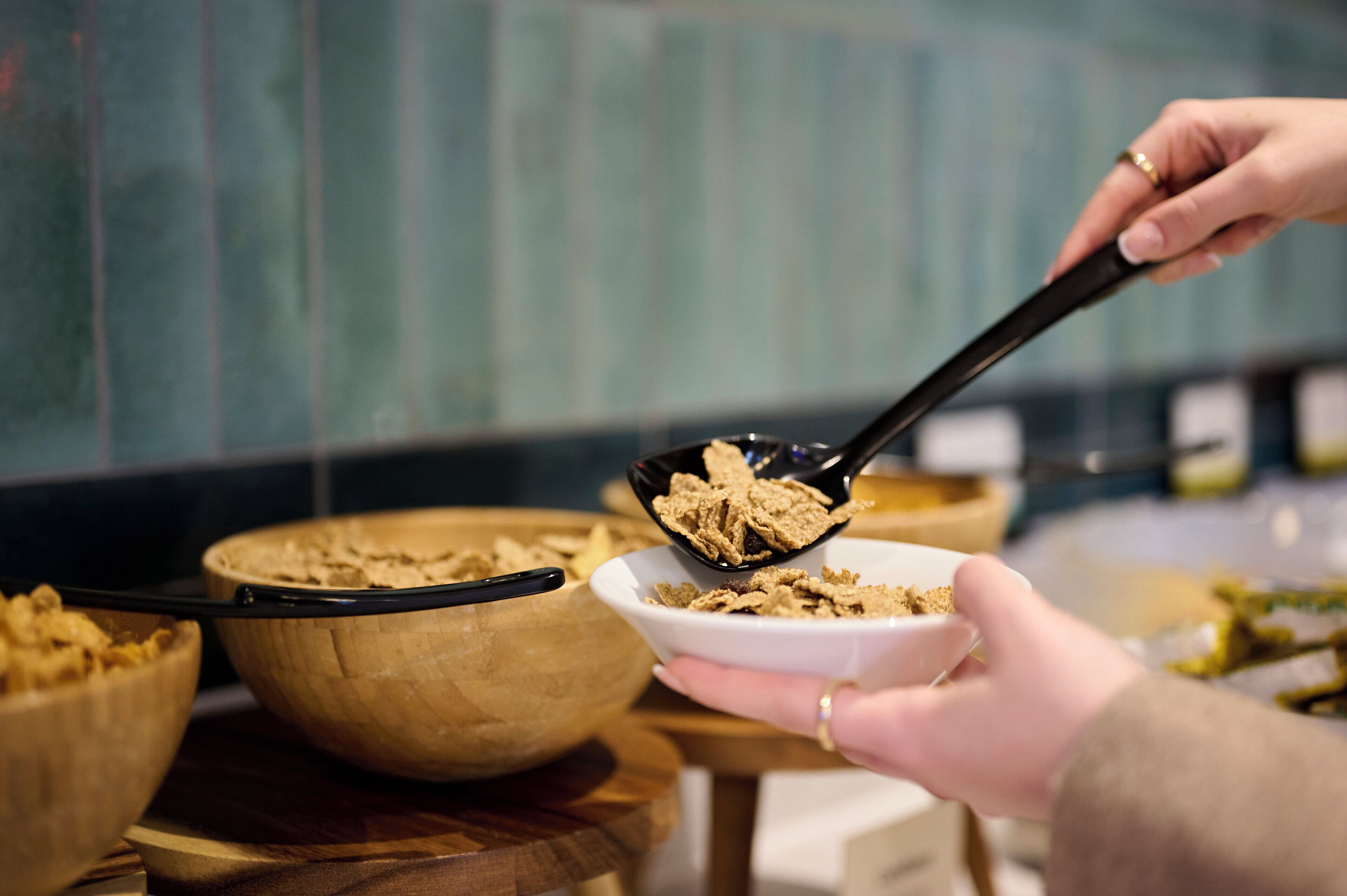 A person serving cereal from a bowl into a smaller bowl.