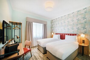 A hotel room with two beds, a desk with a chair, a TV, and a mirror. - Garner Hotel Birmingham South East by IHG (Birmingham)