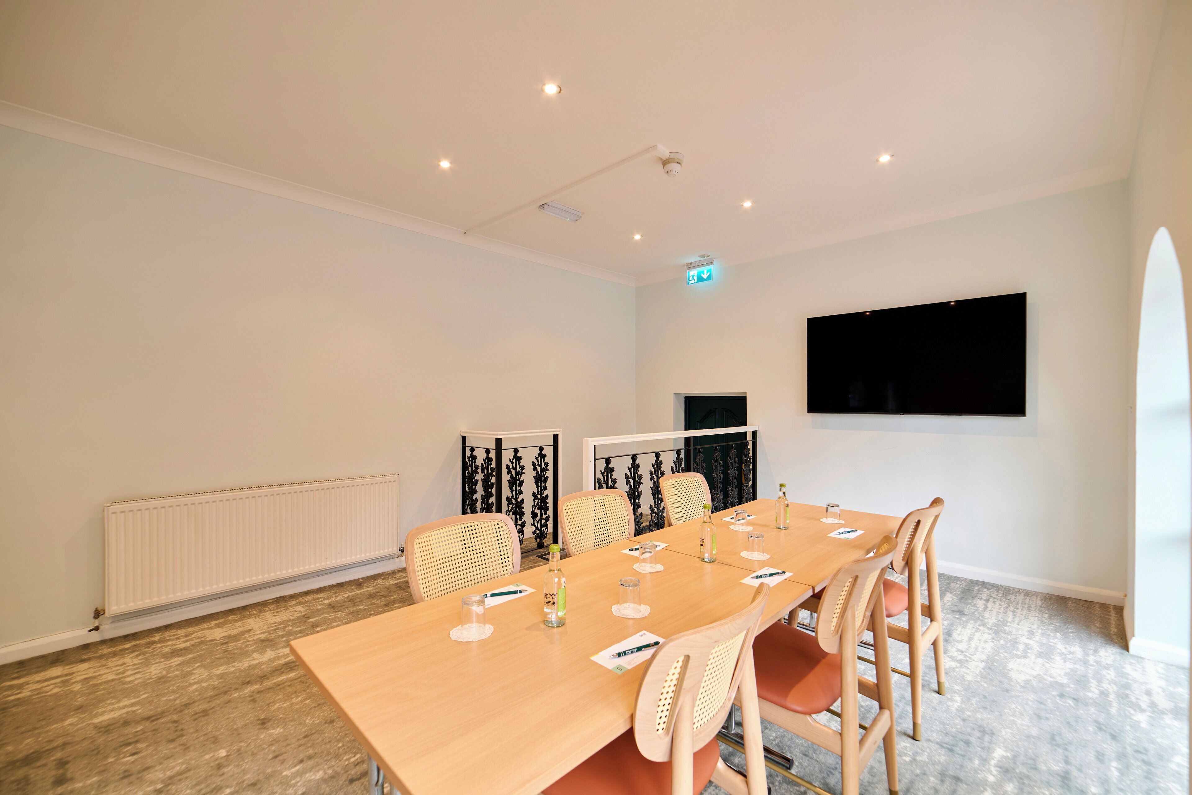A conference room with a long table, six chairs, a projector screen, and a whiteboard.