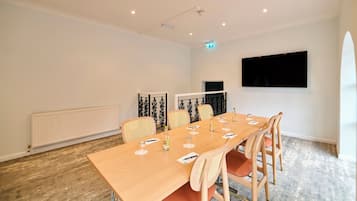 A conference room with a long table, six chairs, a projector screen, and a whiteboard.