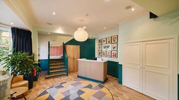 A hotel lobby with a reception desk, a staircase, and a patterned rug.