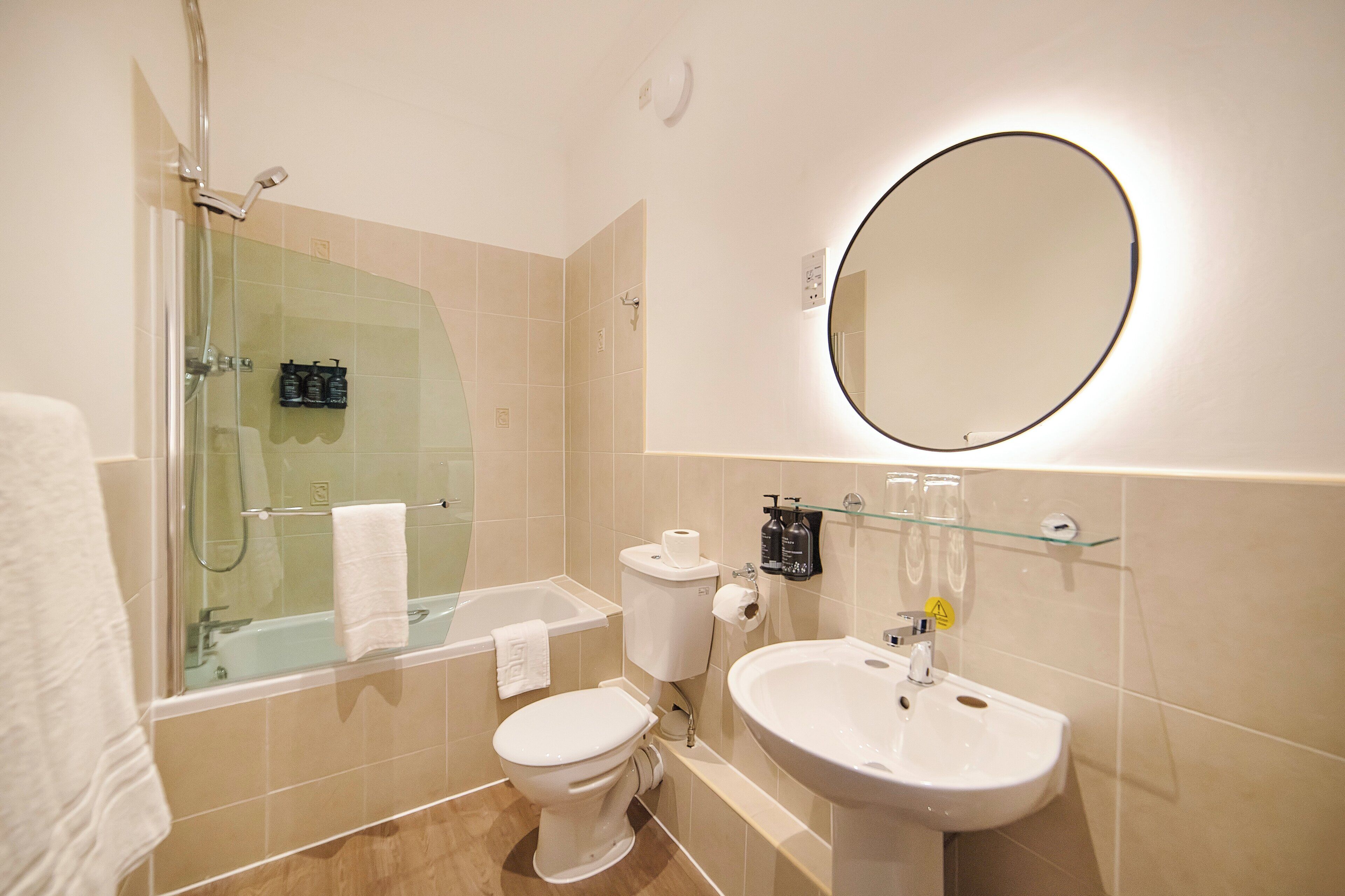 A modern bathroom with a glass-enclosed shower, a toilet, a sink, and a large mirror.