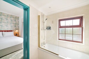 A hotel room with a bed, a shower area with a glass door, and a window with a view. - Garner Hotel Birmingham South East by IHG (Birmingham)