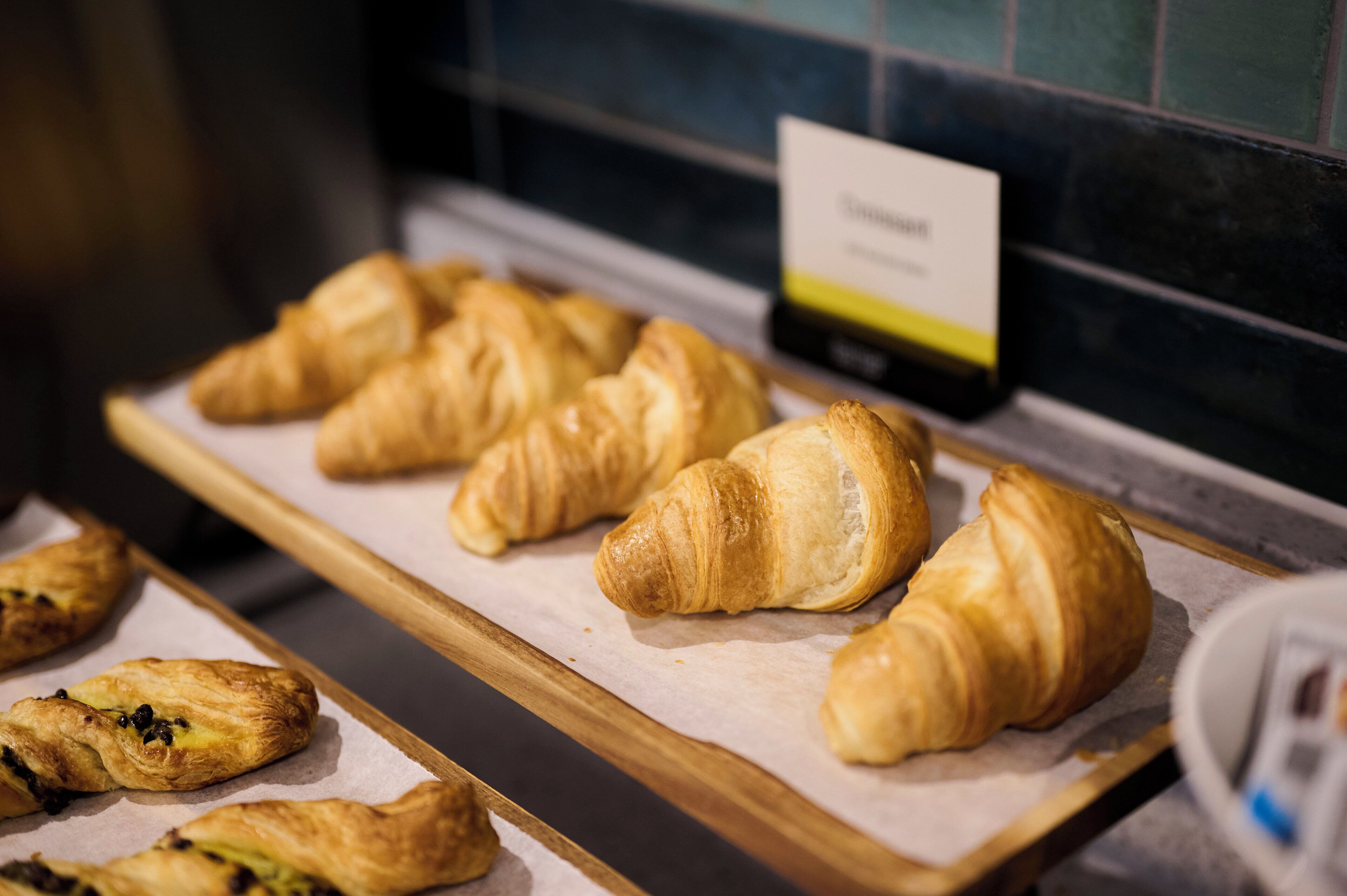 A display of croissants on a wooden board in a bakery.