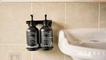 Two black bottles of Urban Skincare products mounted on a wall next to a white sink.