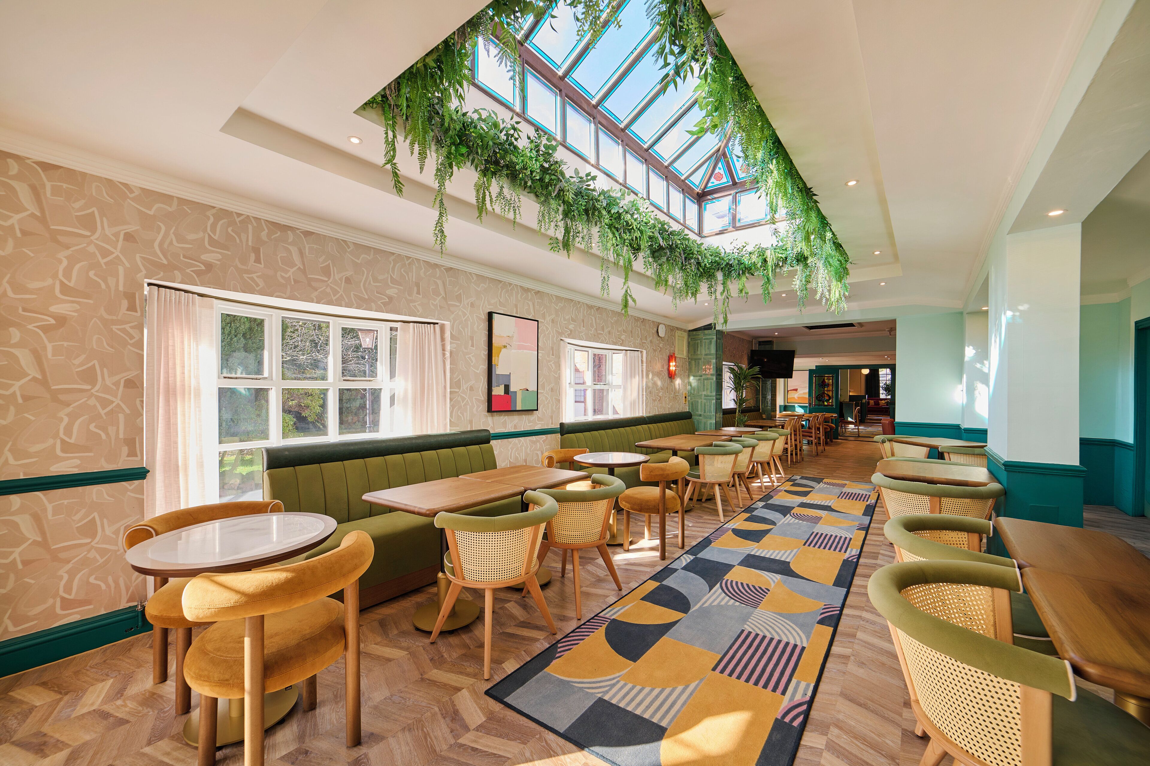 A restaurant with a high ceiling, green seating, and a patterned floor.