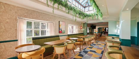 A restaurant with a high ceiling, green seating, and a patterned floor.