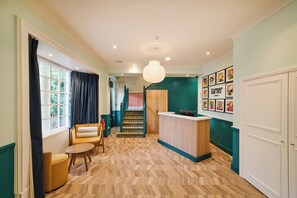 A spacious hallway with a wooden herringbone floor, a reception desk, a staircase, and a seating area with a sofa and armchairs. - Garner Hotel Birmingham South East by IHG (Birmingham)