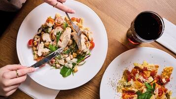 A dining table with plates of food, a glass of red wine, and a napkin.