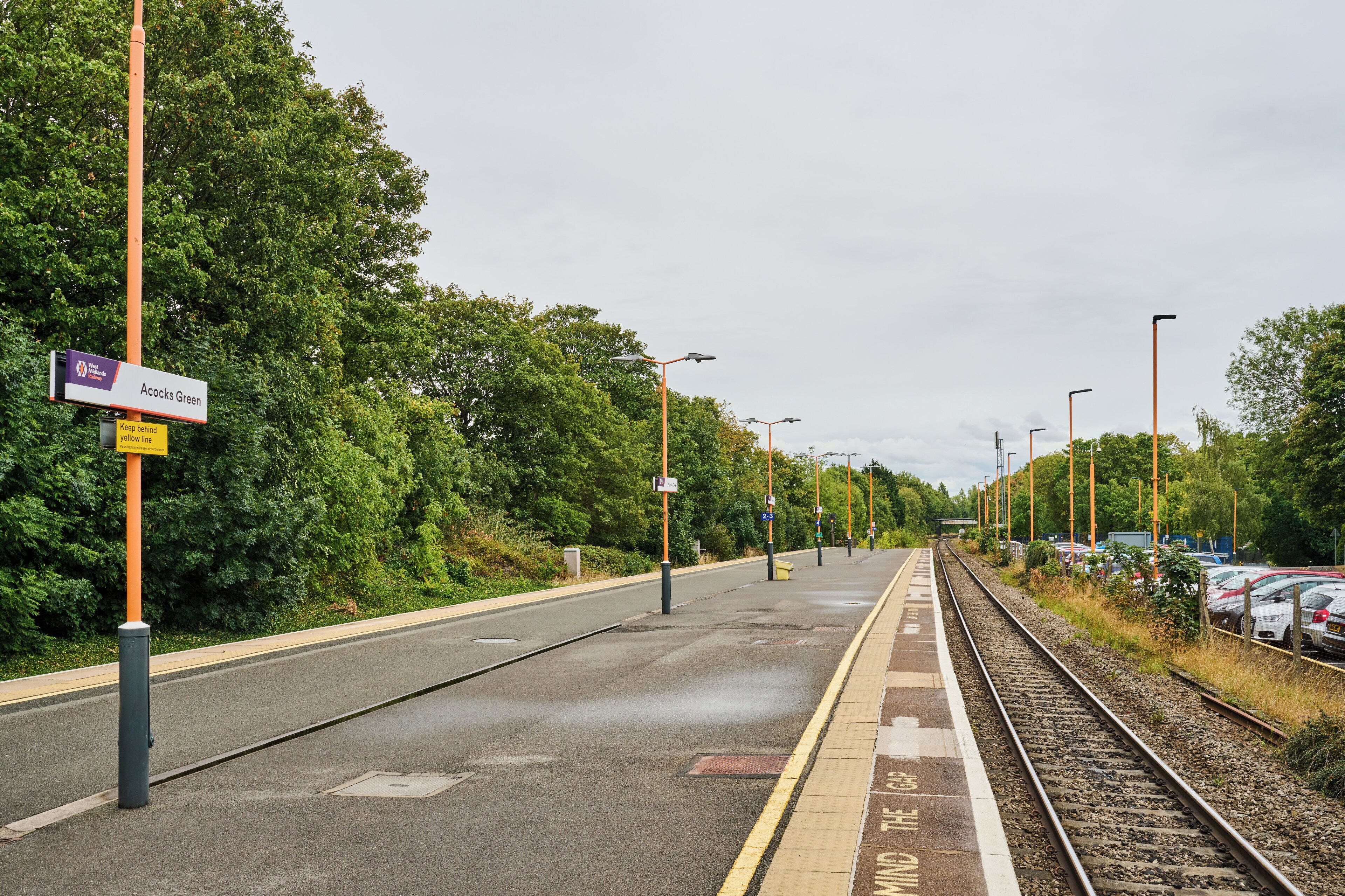 A railway station platform with a sign for Acocks Green.