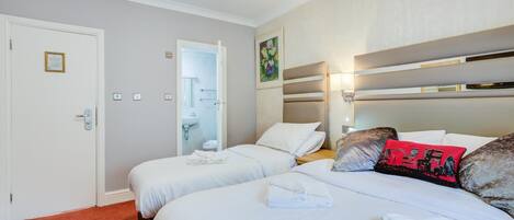 Habitación de hotel con dos camas, un baño y una puerta con placa.