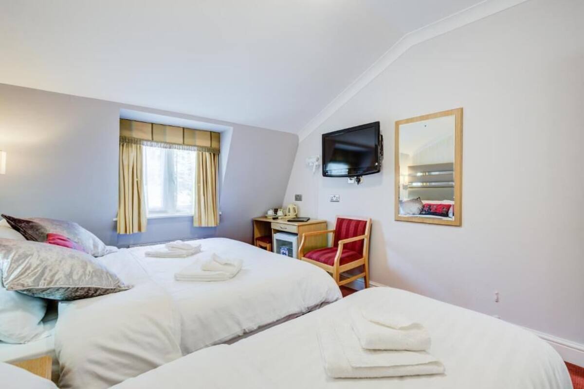 Una habitación de hotel con dos camas, un escritorio, una silla, un televisor y un espejo.