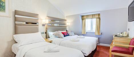 A hotel room with two beds, a desk, a chair, and a television.