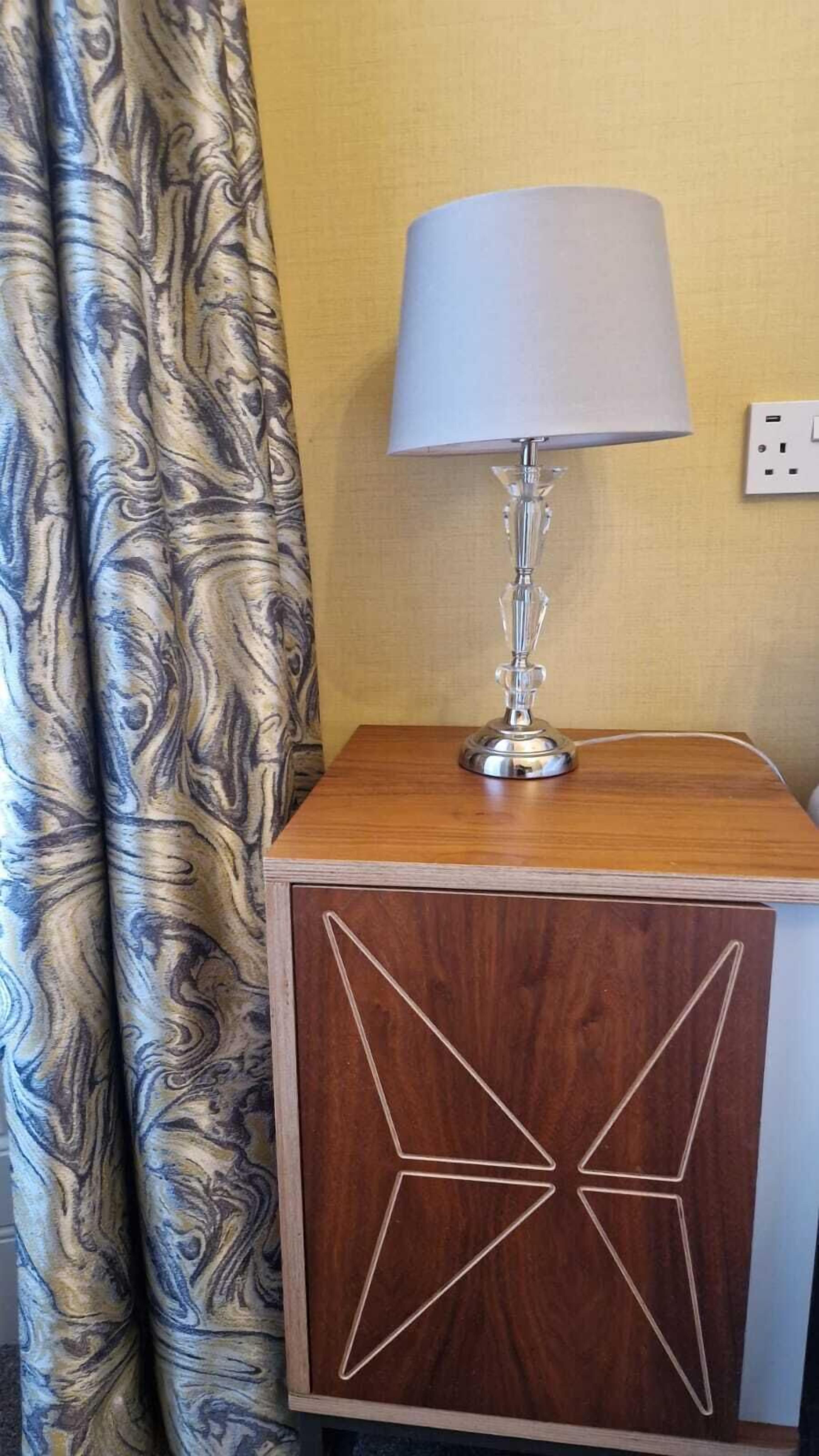 Ein Nachttisch aus Holz mit Lampe und Steckdose.