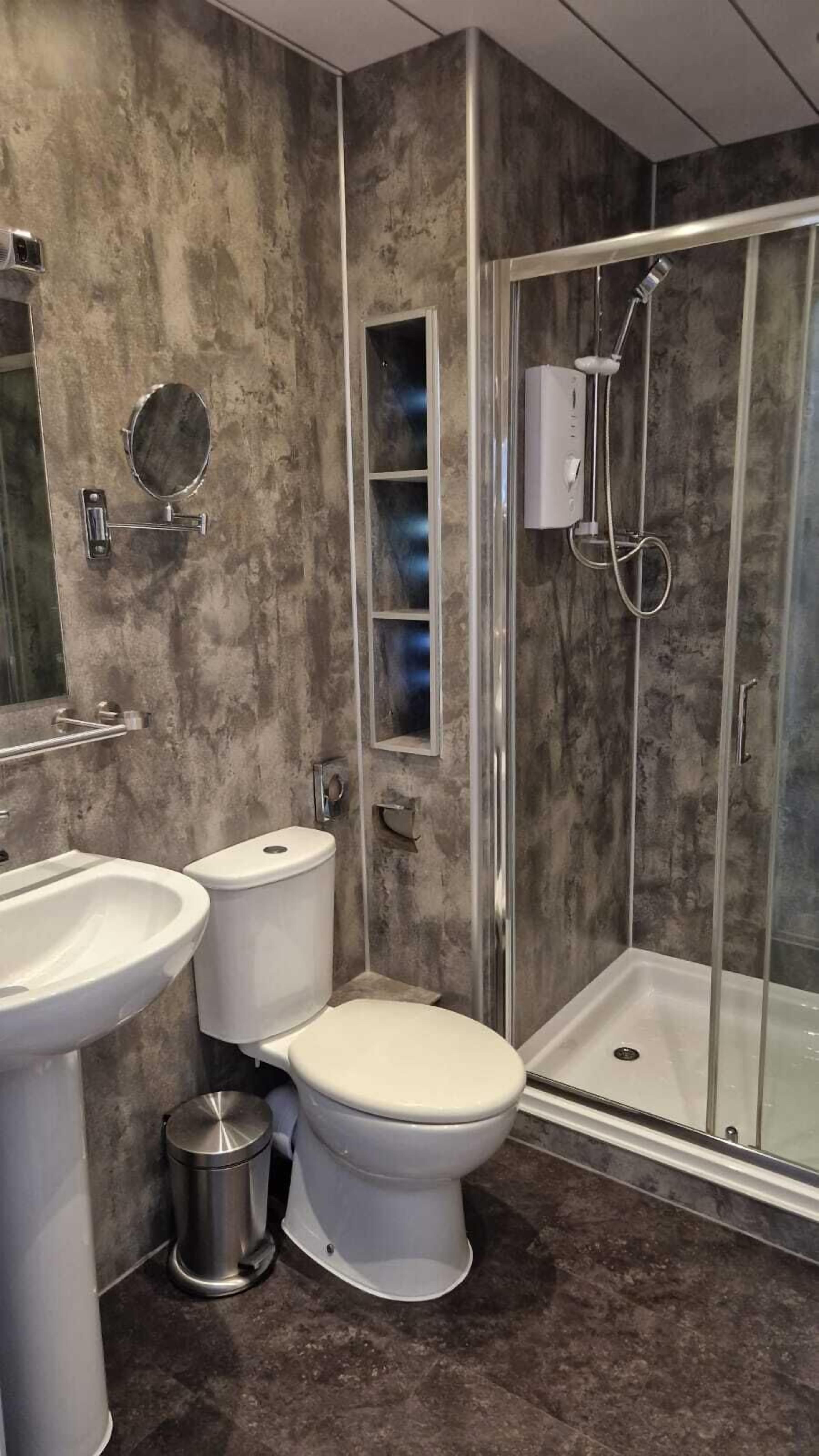 Un baño moderno con ducha, inodoro y lavamanos.