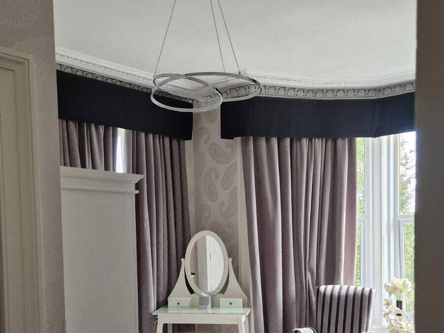 A bedroom with a bed, a vanity with a mirror, a chair, and a ceiling light fixture.